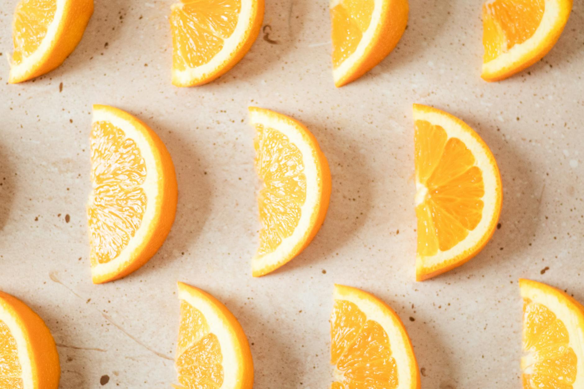 Plastry świeżej pomarańczy ułożone na jasnej, chropowatej powierzchni