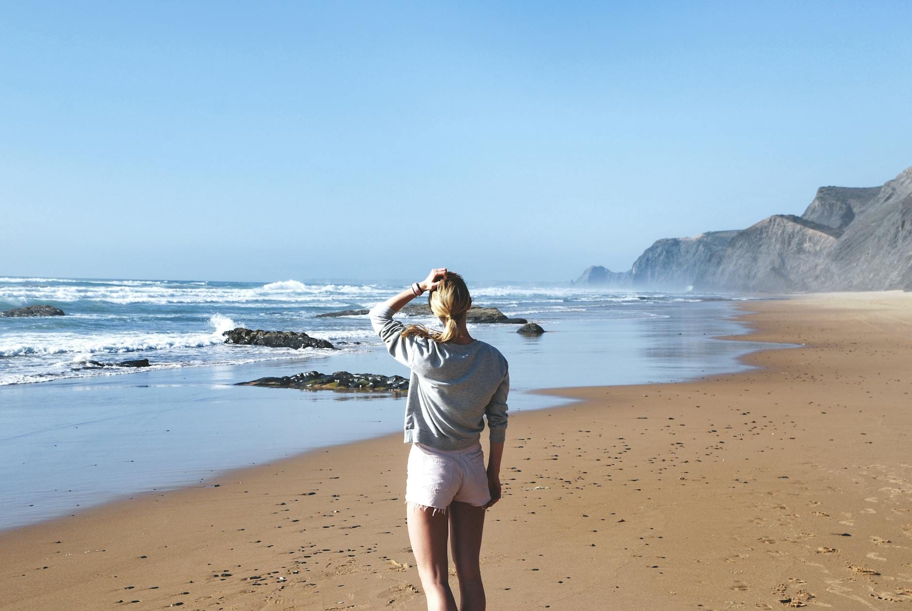 Kobieta na letniej portugalskiej plaży patrzy na ocean