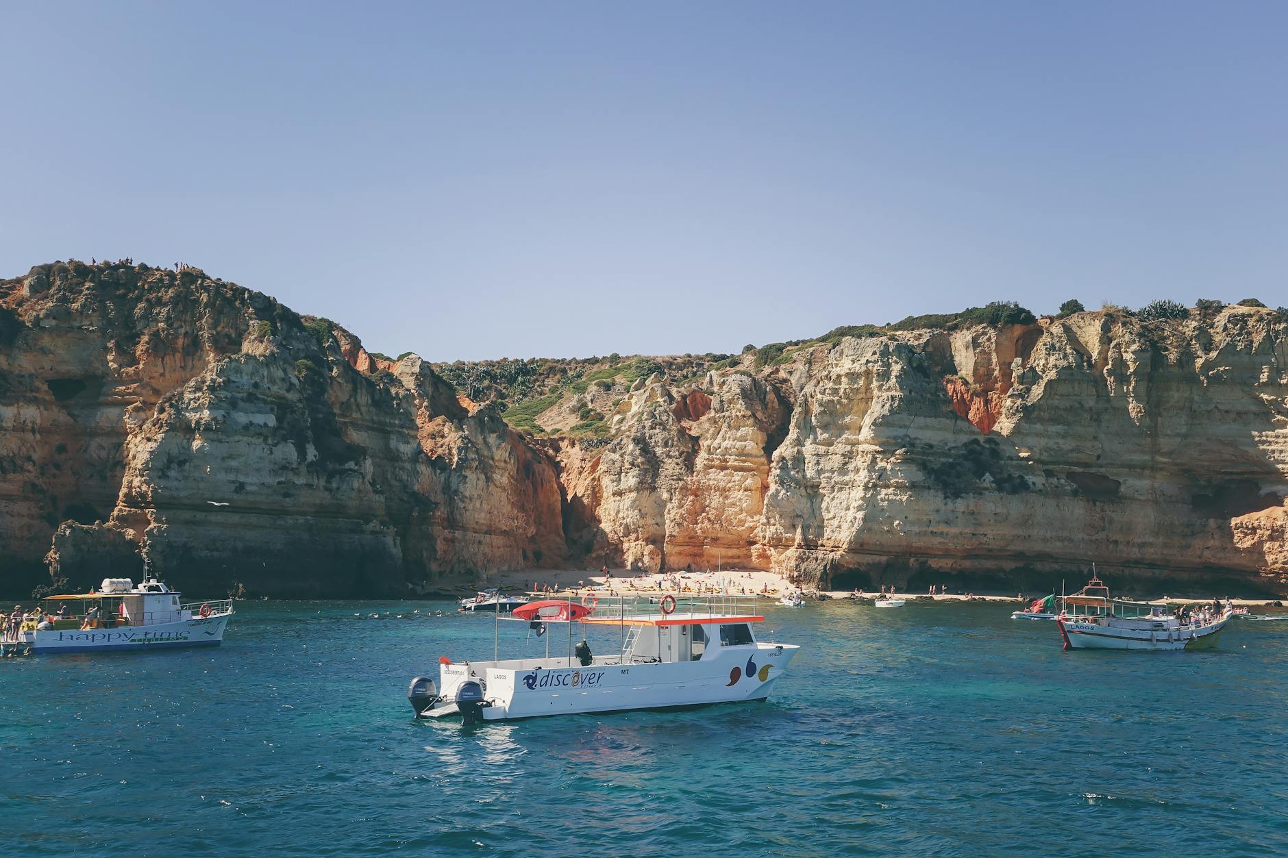 Rejs po wybrzeżu Algarve: jak wybrać łódź, trasę i porę dnia, by cieszyć się klifami bez tłoku Łódź wycieczkowa u stóp skalistych klifów Algarve na błękitnym morzu