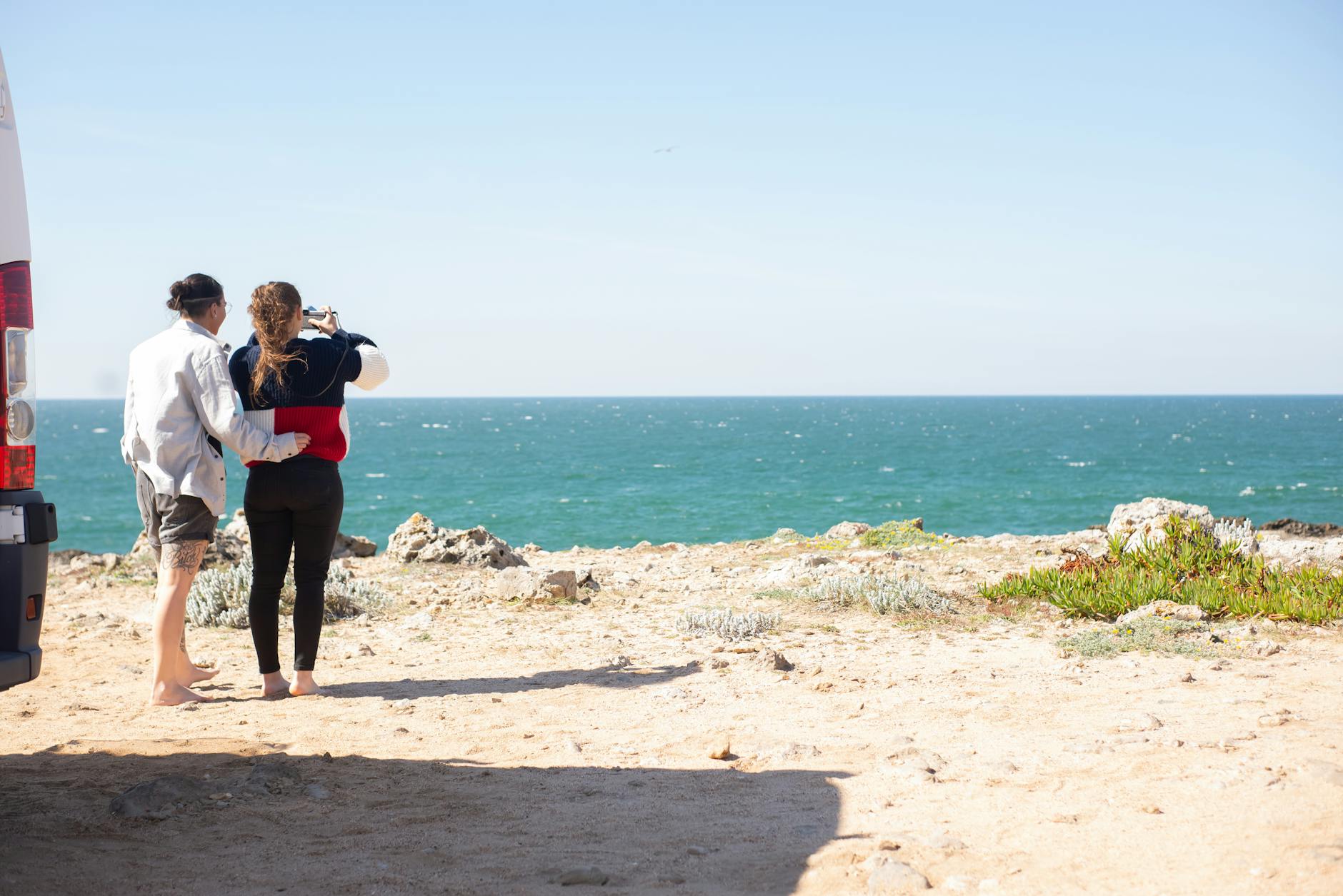 Para przy kamperze podziwia ocean podczas objazdowej podróży po Portugalii