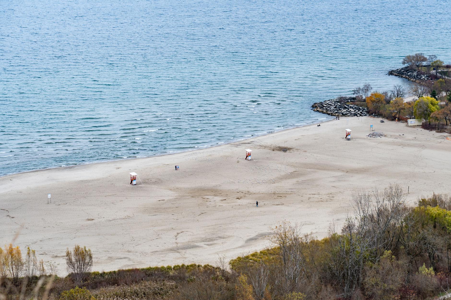 Pusta jesienna plaża z wieżami ratowników i kolorowymi drzewami