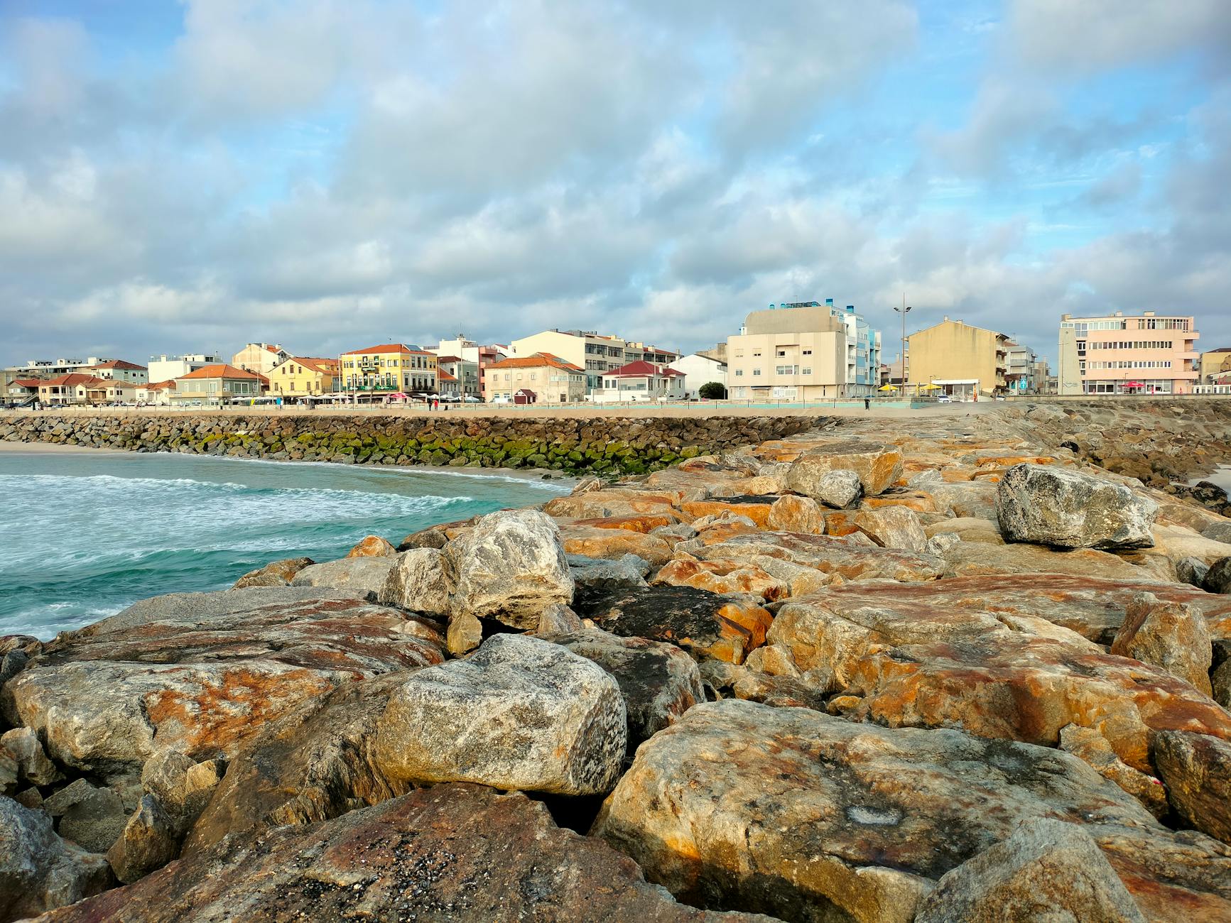 Skalista plaża i zabudowa nadmorskiego miasta Portugalii pod chmurami