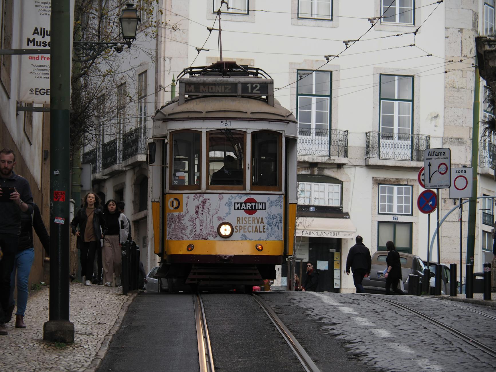 Żółty tramwaj wśród wąskich ulic dzielnicy Alfama w Lizbonie