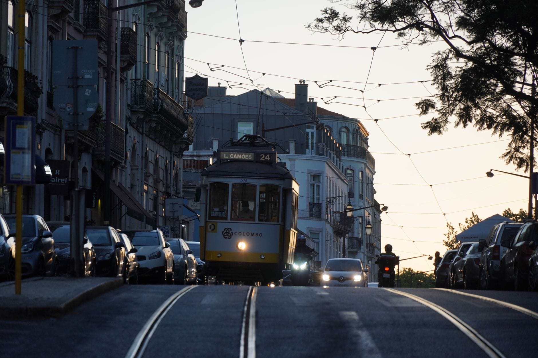 Tramwaj 28 jedzie wąską ulicą Lizbony o zmierzchu