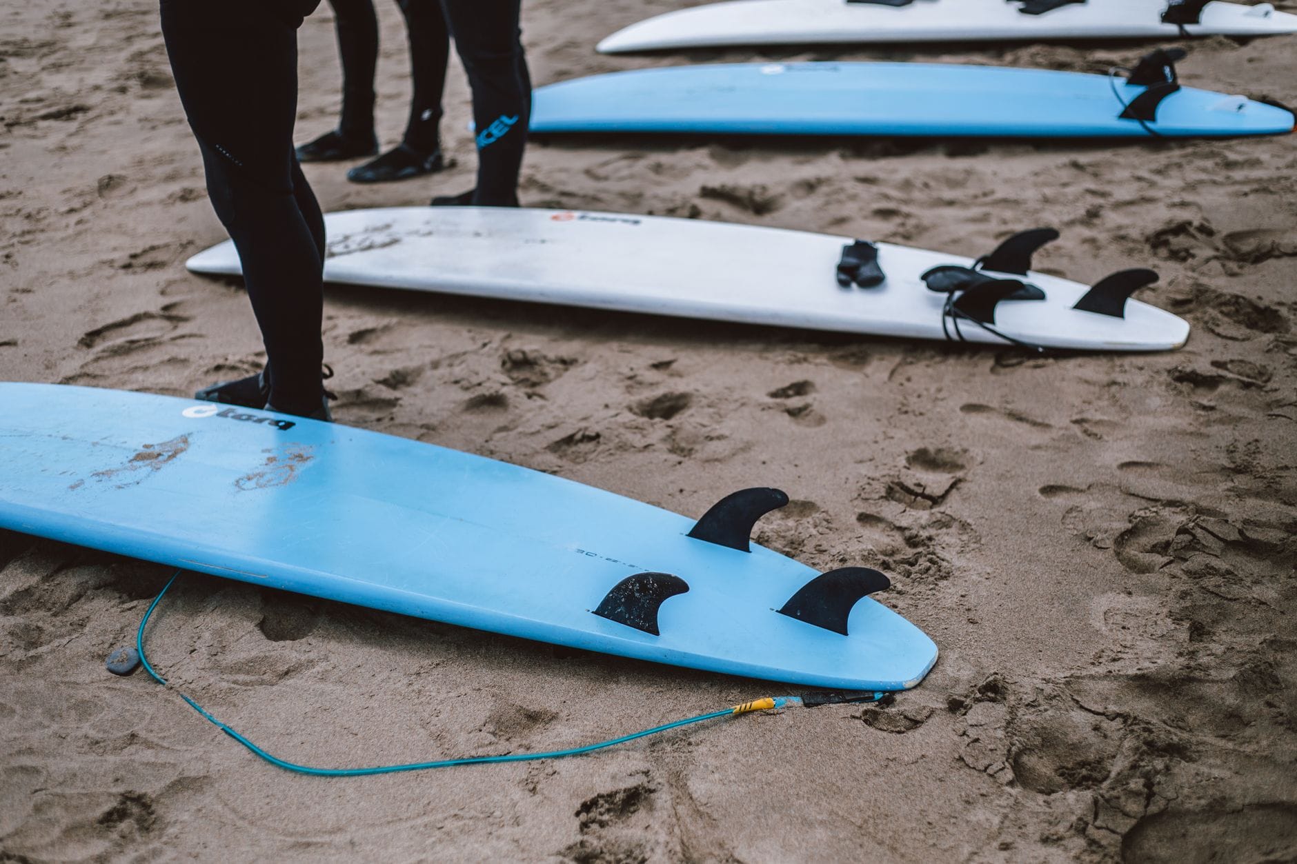 Deski surfingowe na piaszczystej plaży, surferzy szykują się do wejścia do wody
