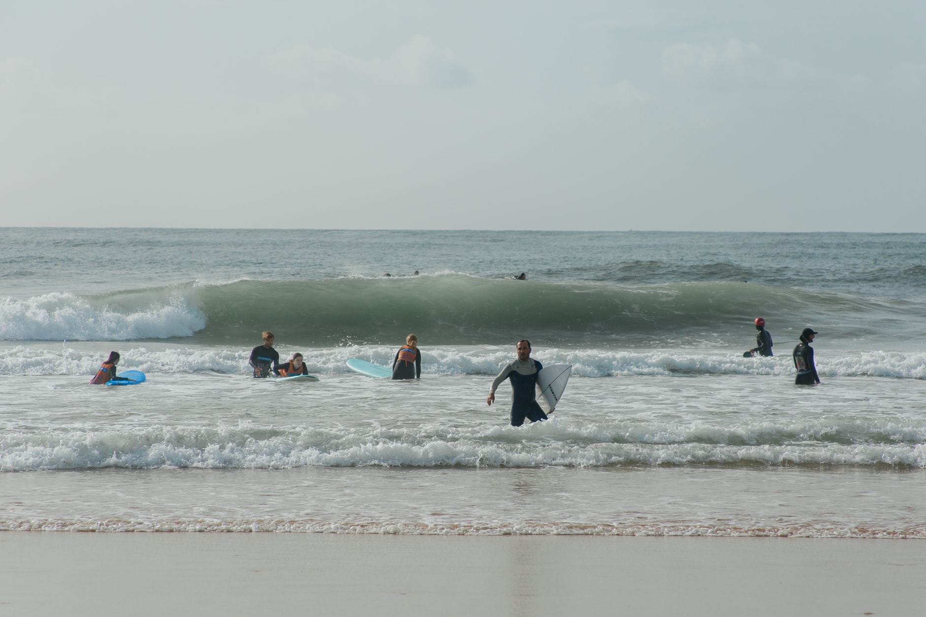 Grupa surferów bawiących się na falach przy plaży w Ericeirze Grupa surferów bawiących się na falach przy plaży w Ericeirze