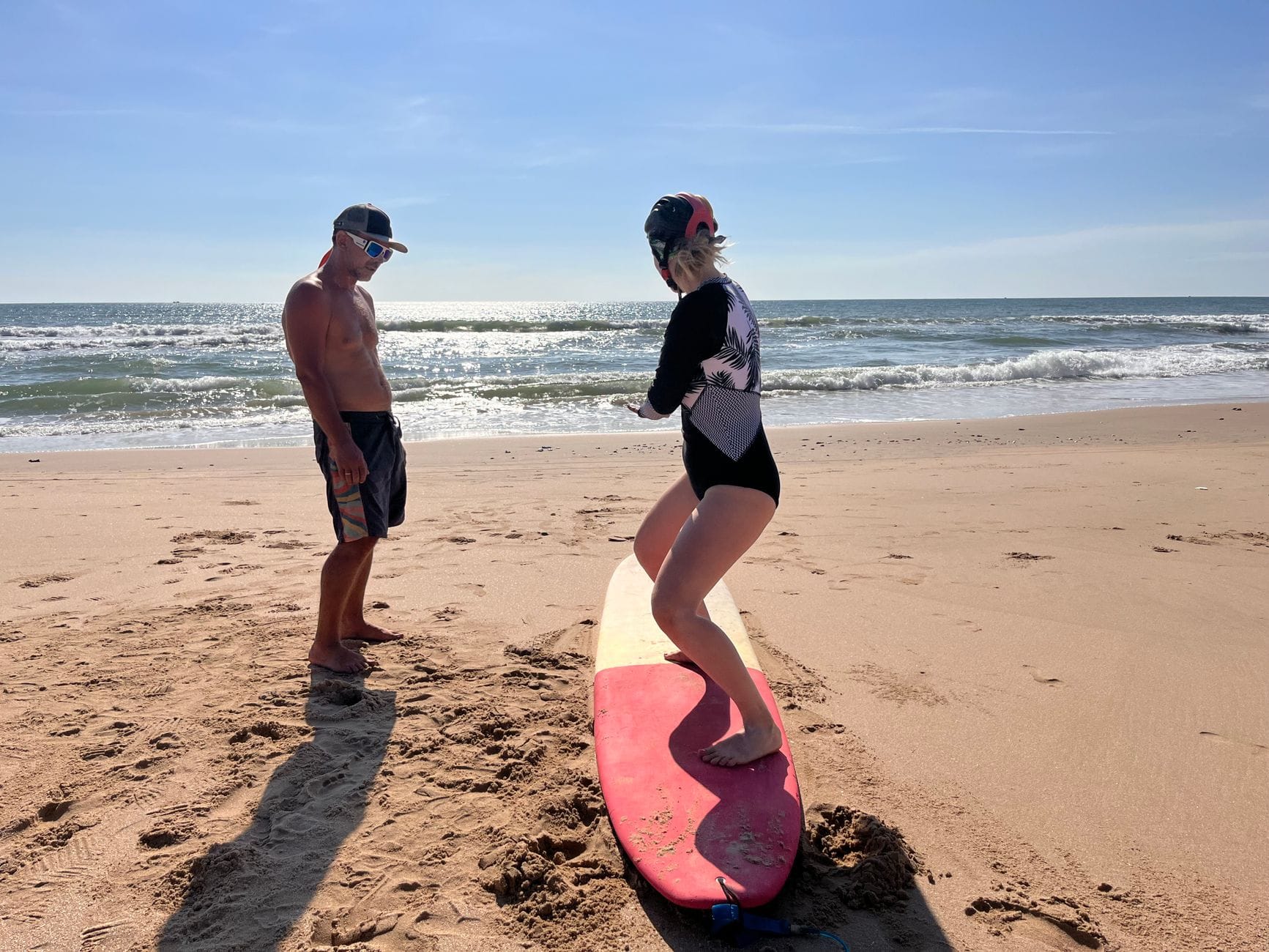 Kobieta uczy się surfować z instruktorem na słonecznej plaży
