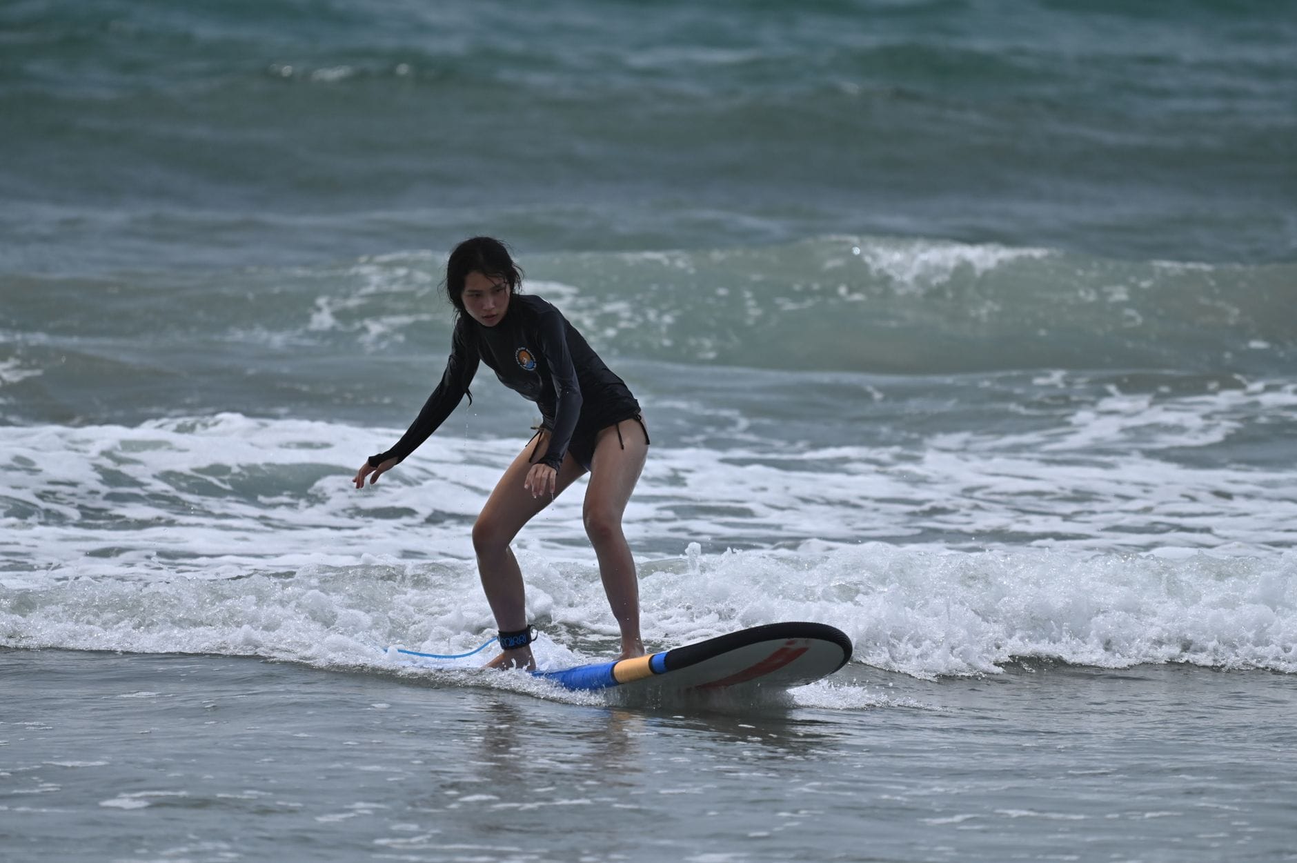 Początkująca surferka łapie małe fale na desce przy plaży