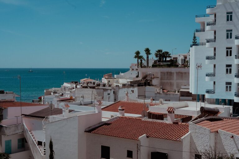 Białe budynki i palmy w miasteczku Algarve z widokiem na ocean